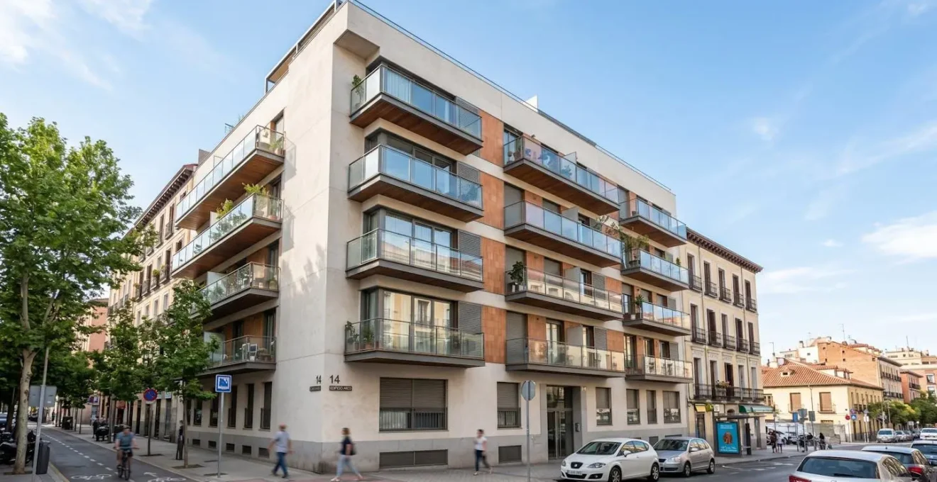 Edificio residencial de cinco plantas con fachada contemporánea de vidrio y metal en zona urbana española bajo luz diurna